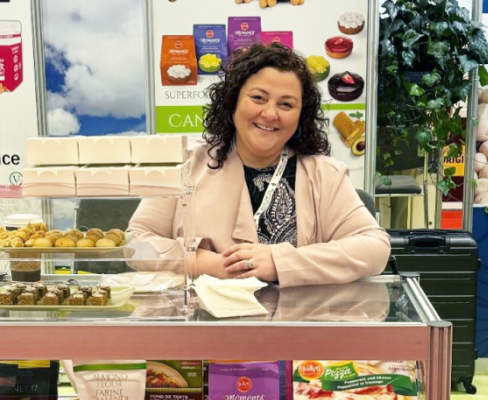 The founder of Piccola Cuccina stands behind a table at a trade show